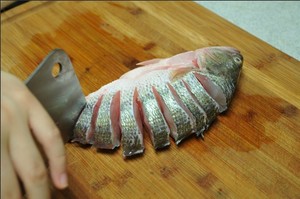 將鱸魚(yú)清洗干凈，從脊椎處切斷至腹部，腹部保留1cm左右不要切斷。